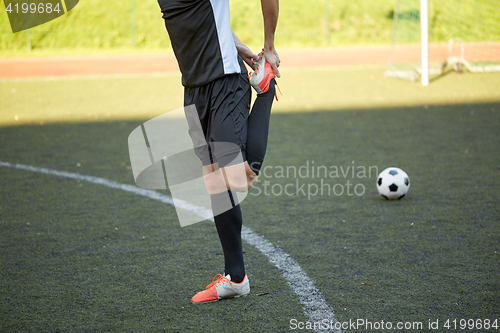 Image of soccer player stretching leg on field football