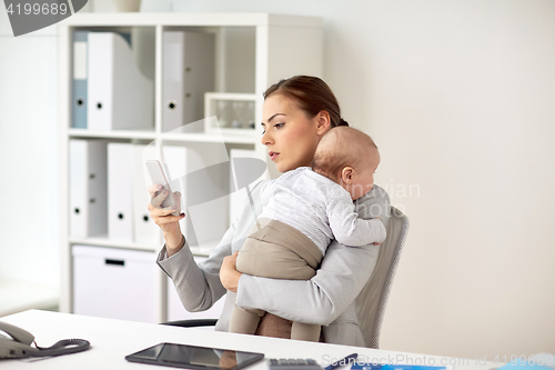 Image of businesswoman with baby and smartphone at office