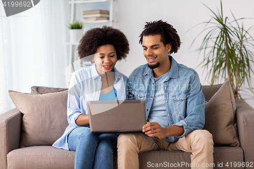 Image of smiling happy couple with laptop at home