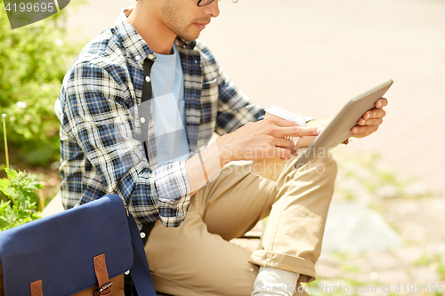 Image of man with tablet pc and coffee on city street bench