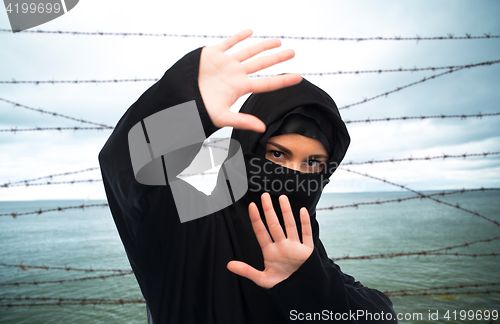 Image of muslim woman in hijab making protective gesture