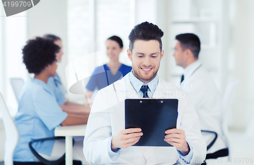 Image of happy doctor with tablet pc over team at clinic