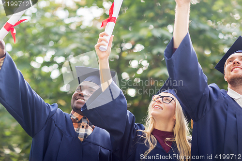 Image of happy students in mortar boards with diplomas