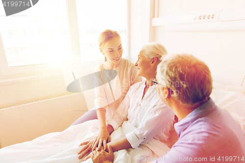 Image of happy family visiting senior woman at hospital