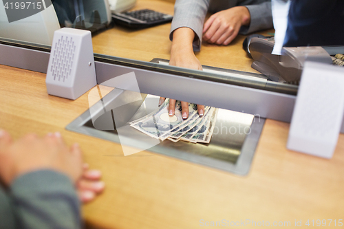 Image of clerk giving cash money to customer at bank office