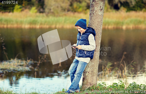 Image of happy boy playing game on smartphone outdoors