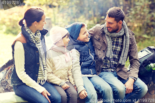 Image of happy family sitting on bench and talking at camp