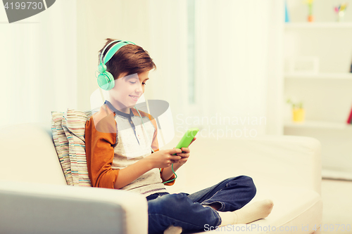 Image of happy boy with smartphone and headphones at home