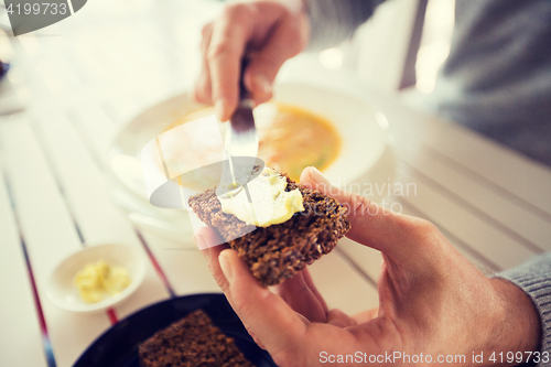 Image of close up of hands applying butter to bread