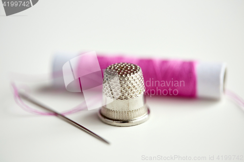 Image of thimble, sewing needle and thread spool