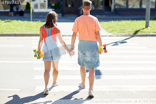 Image of teenage couple with skateboards on city crosswalk