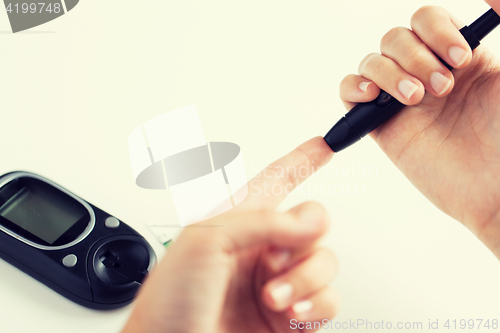 Image of close up of woman making blood test by glucometer