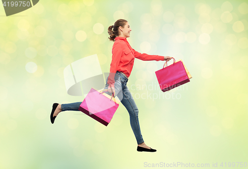 Image of smiling young woman with shopping bags running