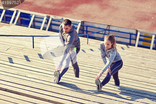 Image of couple stretching leg on stands of stadium