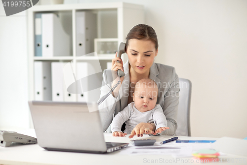 Image of businesswoman with baby calling on phone at office