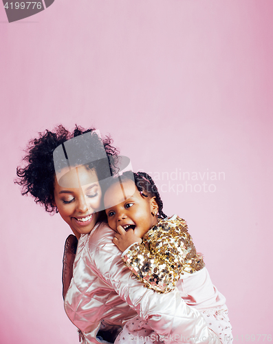 Image of young pretty african-american mother with little cute daughter hugging, happy smiling on pink background, lifestyle modern people concept