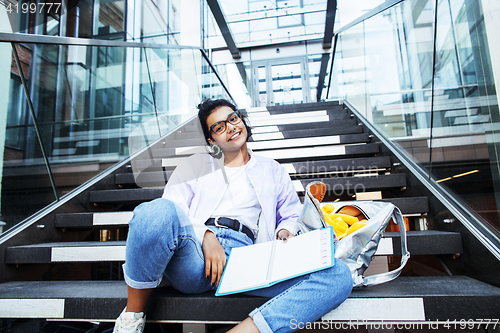 Image of young cute indian girl at university building sitting on stairs 