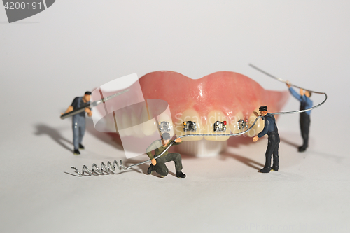 Image of Miniature Workers Performing Dental Procedures. Dental Office Ar