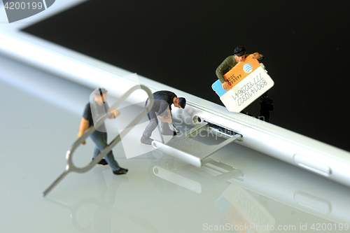 Image of Miniature Workers Installing a SIM Card on a Smart Phone