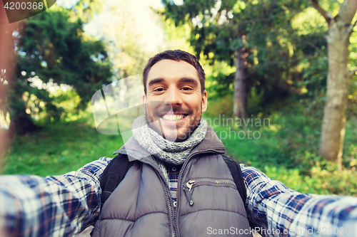 Image of happy man with backpack taking selfie and hiking