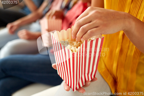 Image of close up of happy friends eating popcorn at home