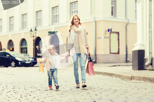 Image of happy mother and child with shopping bags in city