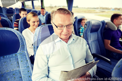 Image of happy senior man reading newspaper in travel bus