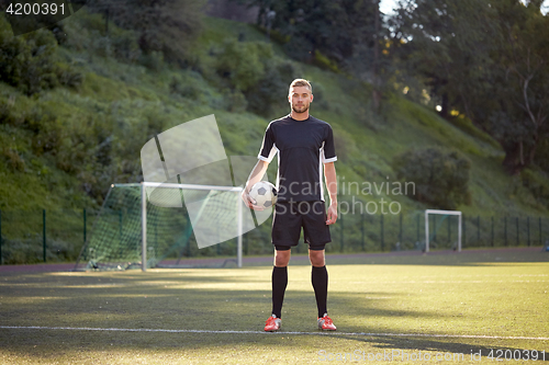 Image of soccer player with ball on football field