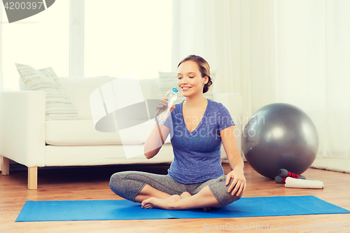 Image of happy woman with water bottle exercising at home