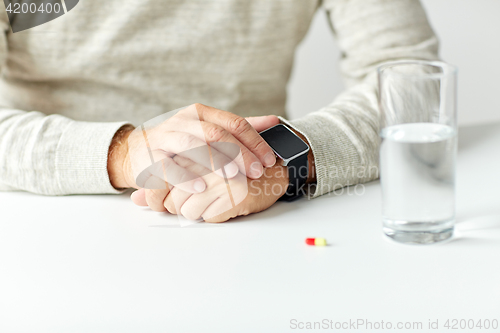 Image of close up of senior man with water, pill and watch