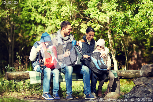 Image of happy family with backpacks and thermos at camp