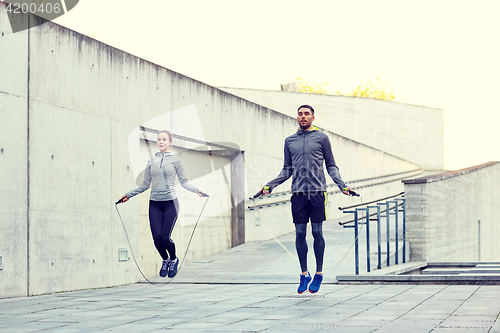 Image of man and woman exercising with jump-rope outdoors