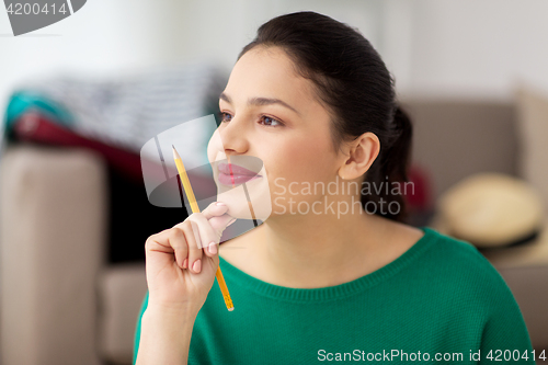 Image of happy young woman with pencil thinking