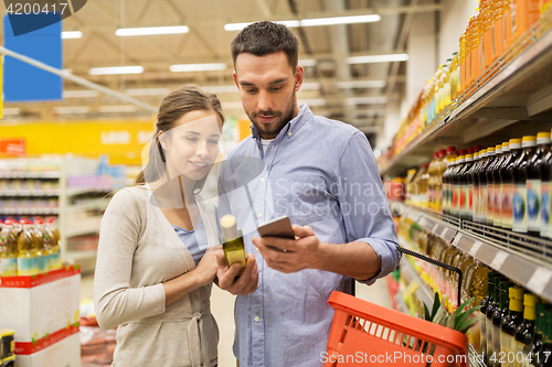 Image of couple with smartphone buying olive oil at grocery