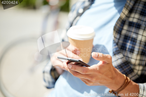 Image of man with smartphone and coffee on city street