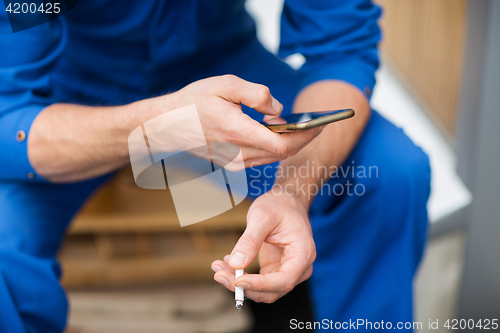 Image of auto mechanic smoking cigarette at car workshop