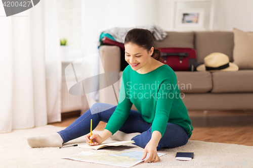 Image of woman with notebook and travel map at home