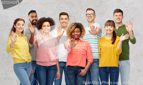 Image of international group of happy people waving hand