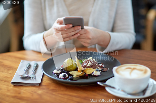 Image of woman with smartphone photographing food at cafe