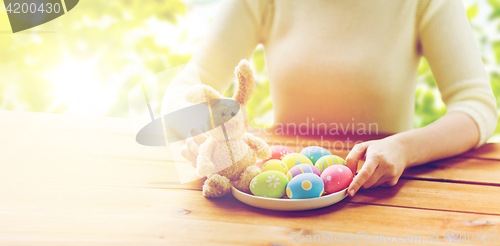 Image of close up of woman hands with easter eggs and bunny