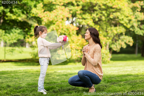 Image of girl giving with flowers to mother in summer park