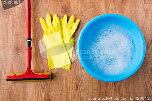 Image of basin with cleaning stuff on wooden background