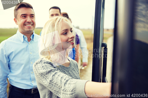 Image of group of happy passengers boarding travel bus