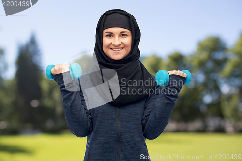 Image of muslim woman in hijab with dumbbells doing fitness