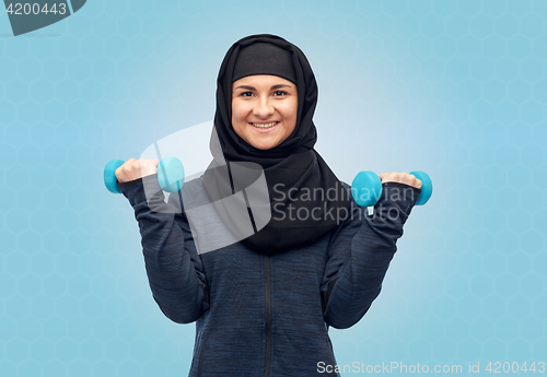 Image of muslim woman in hijab with dumbbells doing fitness
