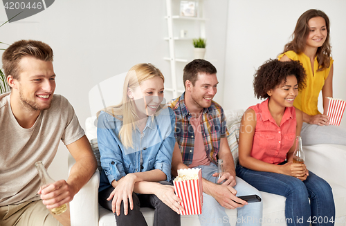 Image of happy friends with popcorn watching tv at home
