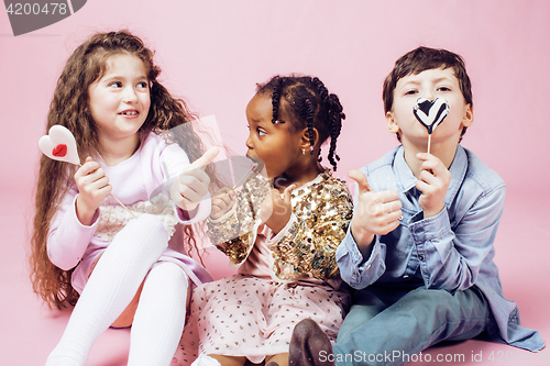 Image of lifestyle people concept: diverse nation children playing together, caucasian boy with african little girl holding candy happy smiling 