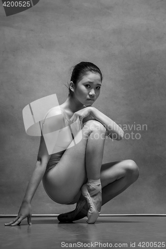 Image of Tired ballet dancer sitting on the wooden chair on a gray background