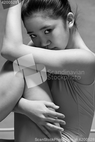 Image of Tired ballet dancer sitting on the gray background