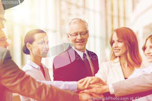 Image of business people putting hands on top in office